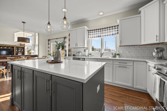 kitchen with stove, dark wood-type flooring, gray cabinetry, backsplash, and a sink