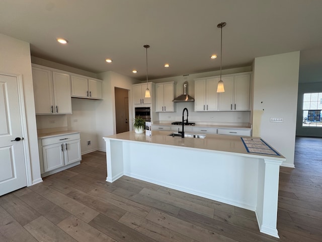 627 Henry Ln, Oswego, IL 60543 - kitchen with wall chimney exhaust hood, wood-type flooring, a large island with sink, white cabinetry, and recessed lighting