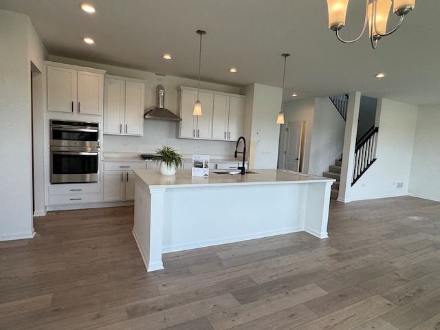 627 Henry Ln, Oswego, IL 60543 - kitchen featuring stainless steel double oven, wall chimney range hood, an island with sink, hardwood / wood-style floors, and recessed lighting