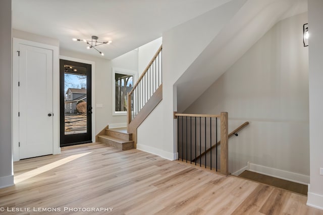 foyer featuring baseboards, wood finished floors, and an inviting chandelier