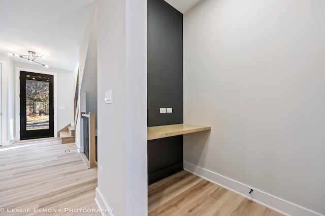 hall with baseboards, light wood-style floors, and stairs