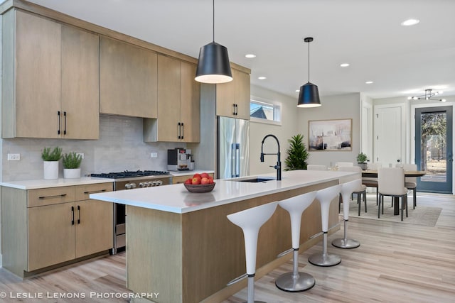 kitchen featuring light countertops, a kitchen breakfast bar, stainless steel appliances, and a sink