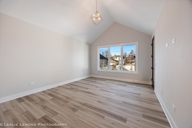 interior space featuring light wood-type flooring, vaulted ceiling, and baseboards