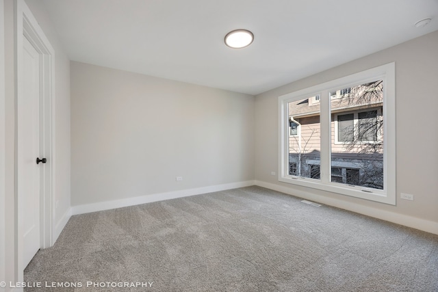 carpeted spare room with visible vents and baseboards