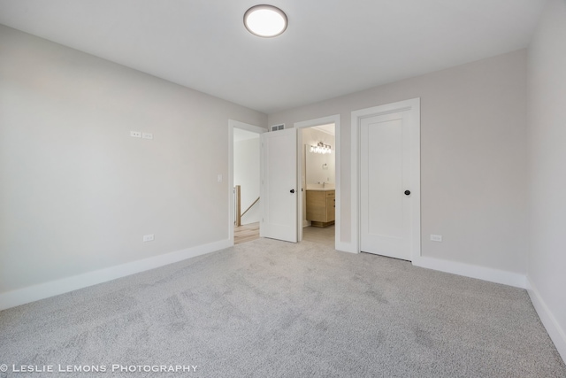 unfurnished bedroom with carpet floors, visible vents, baseboards, and ensuite bathroom