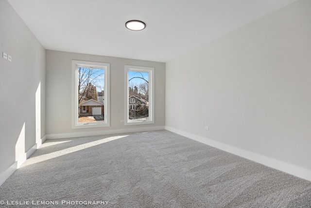 carpeted empty room featuring baseboards