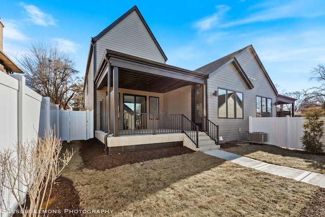view of front of property with cooling unit, a fenced backyard, and covered porch