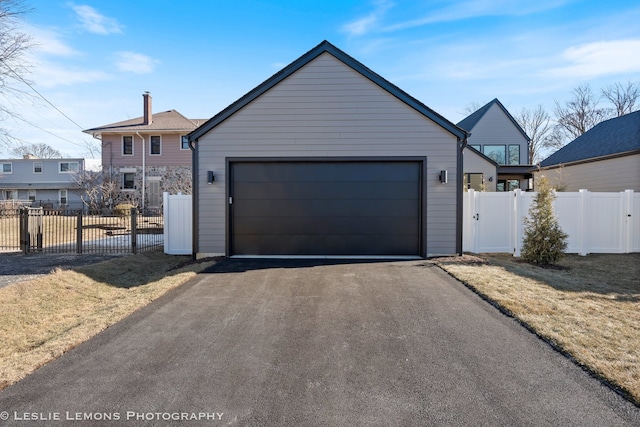 view of front of property featuring fence, aphalt driveway, and a garage