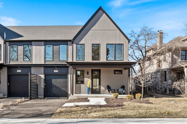 view of front facade with a garage, driveway, a shingled roof, and covered porch