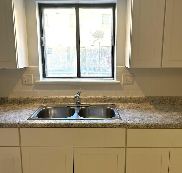 kitchen featuring white cabinetry, tasteful backsplash, and a sink