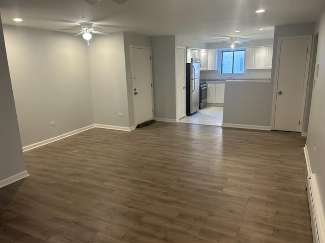 unfurnished living room featuring a baseboard radiator, dark wood-style flooring, baseboards, and a ceiling fan