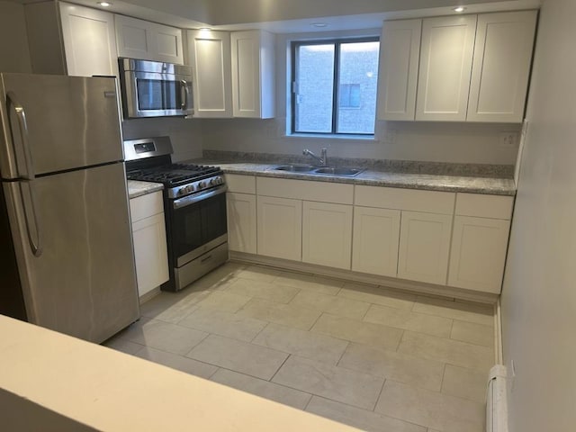 kitchen with a sink, white cabinets, light countertops, and appliances with stainless steel finishes