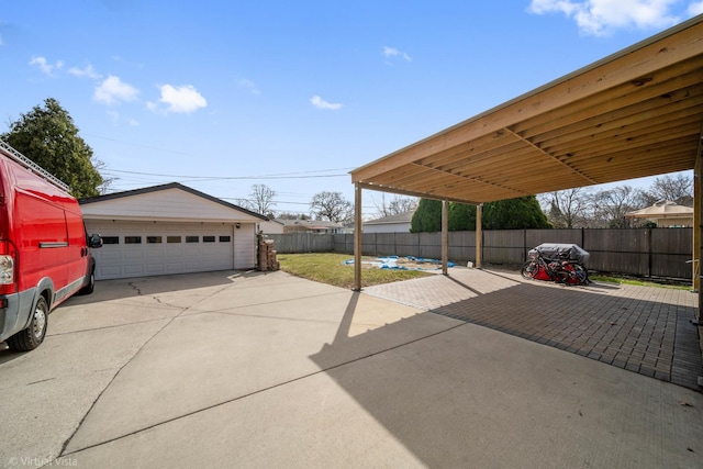 view of patio with a garage, fence, and an outbuilding
