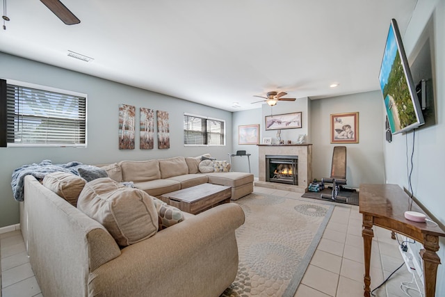living area featuring visible vents, a tile fireplace, light tile patterned flooring, and ceiling fan