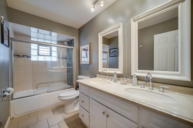 bathroom with double vanity, a sink, toilet, and tile patterned floors