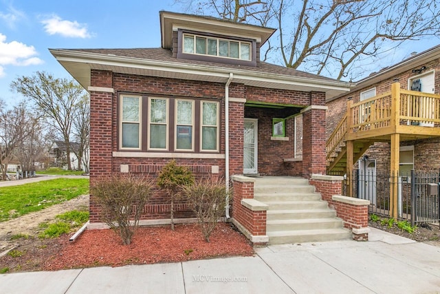 view of front of home with brick siding, fence, and stairway