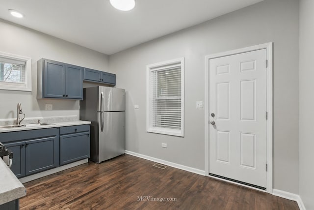 kitchen featuring dark wood-style flooring, a sink, freestanding refrigerator, and light countertops