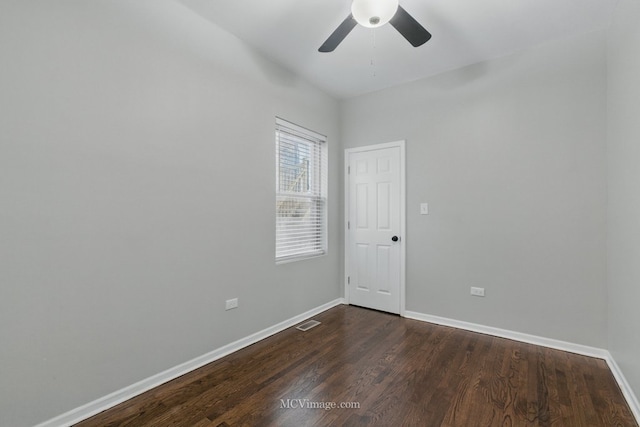 unfurnished room featuring visible vents, a ceiling fan, dark wood finished floors, and baseboards