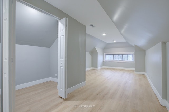 additional living space with baseboards, visible vents, light wood finished floors, and lofted ceiling