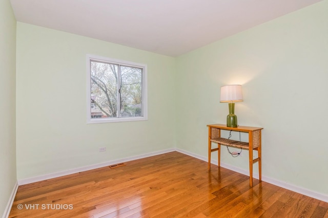spare room featuring hardwood / wood-style flooring, baseboards, and visible vents