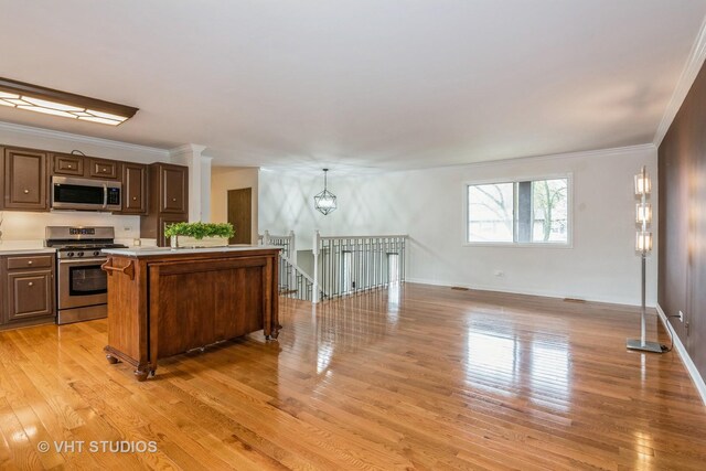 kitchen featuring a center island, light wood-style flooring, appliances with stainless steel finishes, light countertops, and ornamental molding
