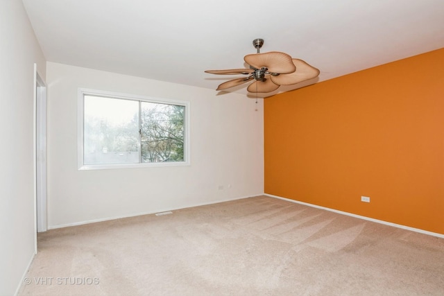carpeted empty room featuring baseboards and a ceiling fan