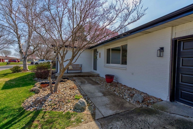 entrance to property with a lawn, brick siding, and a porch
