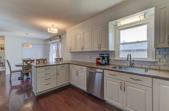 kitchen with dark wood-style flooring, a peninsula, white cabinetry, a sink, and stainless steel dishwasher