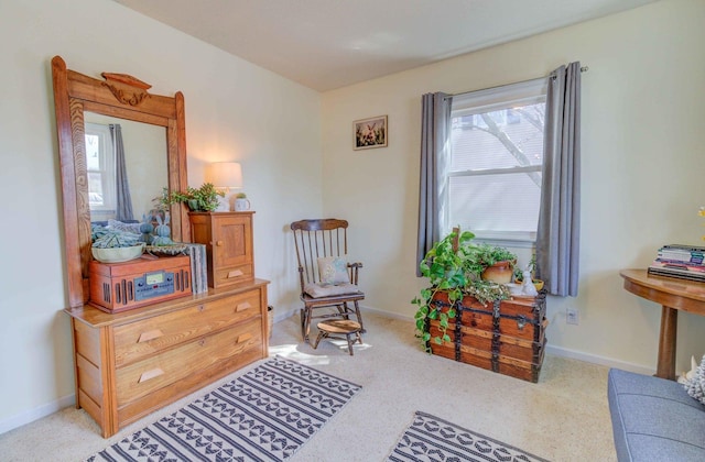 living area with baseboards and light colored carpet