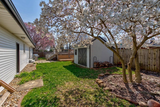 view of yard with a fenced backyard, a storage unit, a wooden deck, and an outbuilding