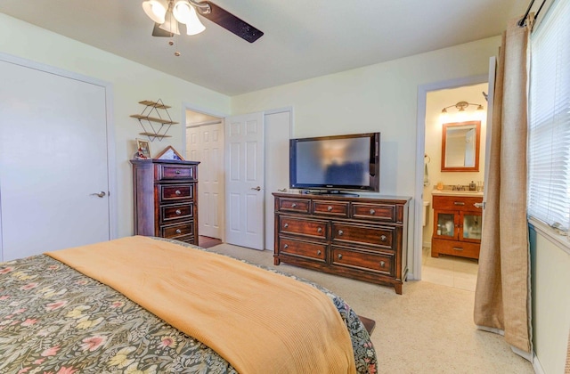 bedroom featuring connected bathroom, light colored carpet, a closet, and ceiling fan