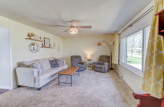 living room featuring baseboards, carpet floors, a textured ceiling, and a ceiling fan