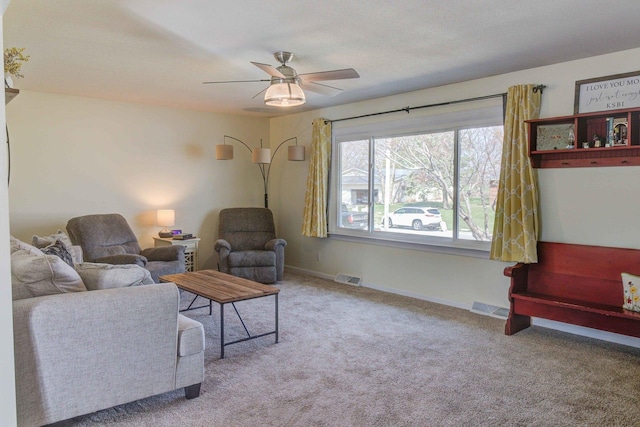 living area with baseboards, a ceiling fan, visible vents, and carpet