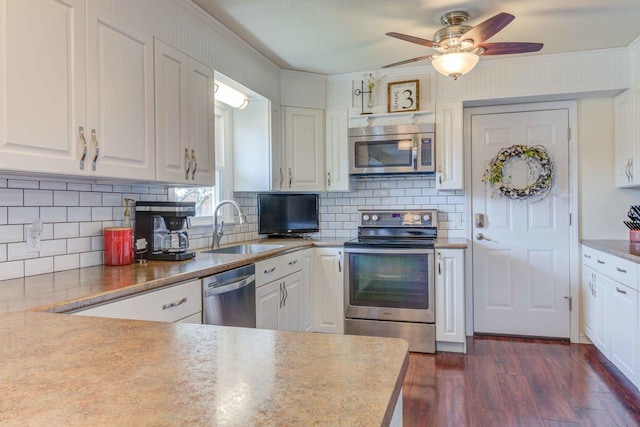 kitchen with stainless steel appliances, a sink, dark wood-style floors, white cabinets, and a ceiling fan