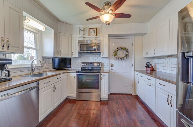 kitchen with white cabinetry, stainless steel appliances, dark wood-type flooring, a sink, and a ceiling fan