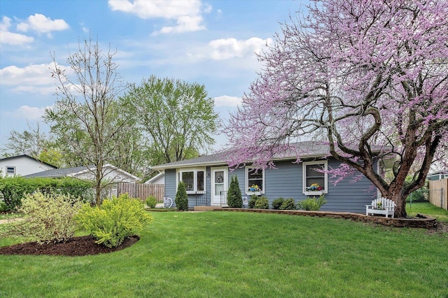 ranch-style house featuring a front lawn and fence