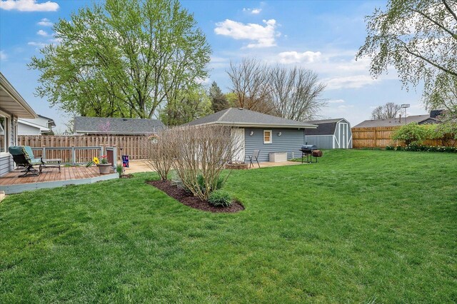 view of yard with a fenced backyard, an outbuilding, a deck, and a shed