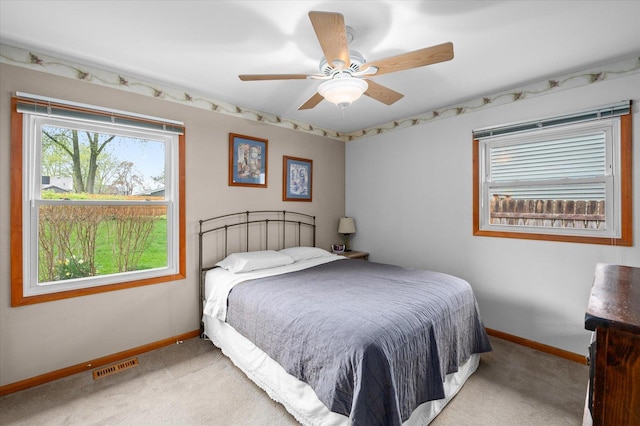 bedroom featuring visible vents, a ceiling fan, baseboards, and light carpet