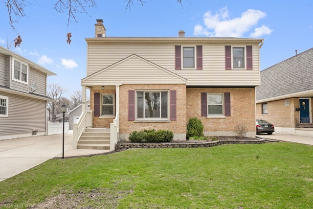 view of front of property with a front yard, brick siding, and a chimney