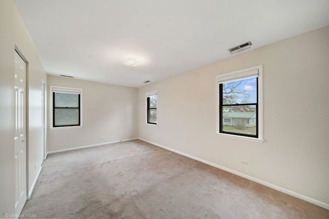 carpeted empty room featuring visible vents and baseboards