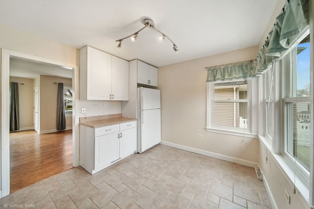 kitchen with white cabinets, light countertops, freestanding refrigerator, and a healthy amount of sunlight