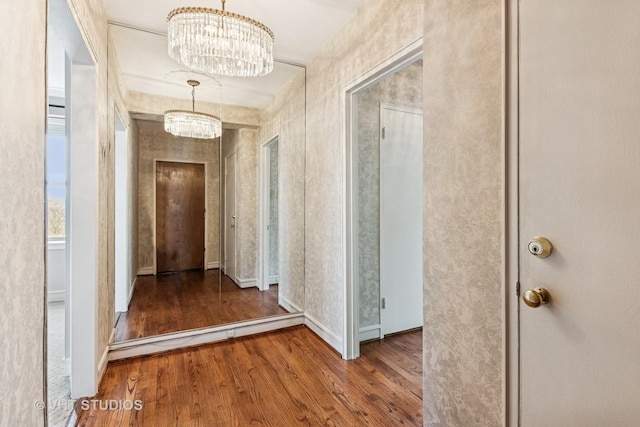 corridor featuring wood finished floors and an inviting chandelier