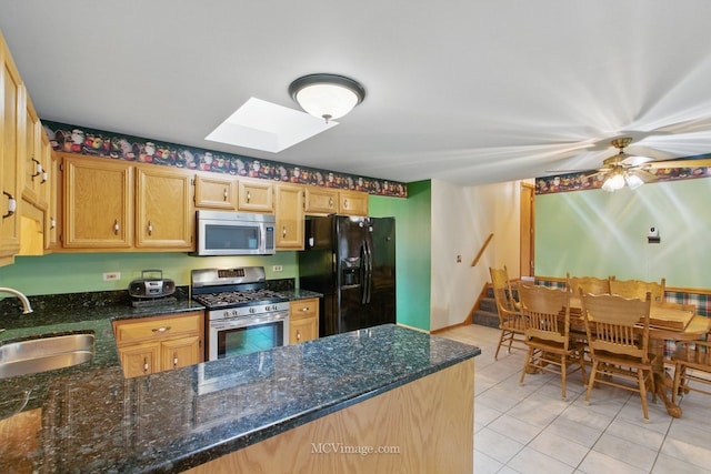 633 Mendota Ln, Romeoville, IL 60446 - kitchen featuring dark stone counters, a peninsula, a skylight, appliances with stainless steel finishes, and a sink