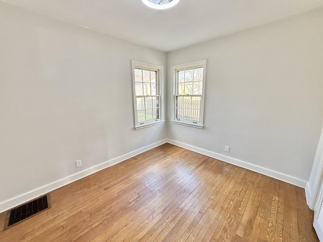 empty room featuring baseboards, visible vents, and wood-type flooring