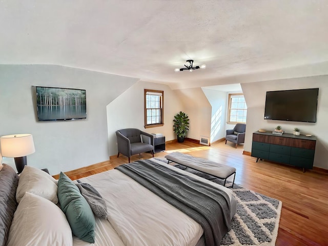 bedroom with visible vents, multiple windows, and wood finished floors