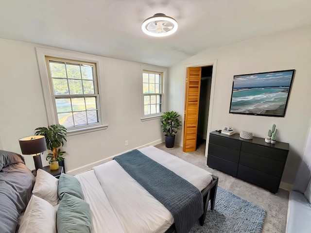 bedroom featuring a closet, vaulted ceiling, baseboards, and light colored carpet