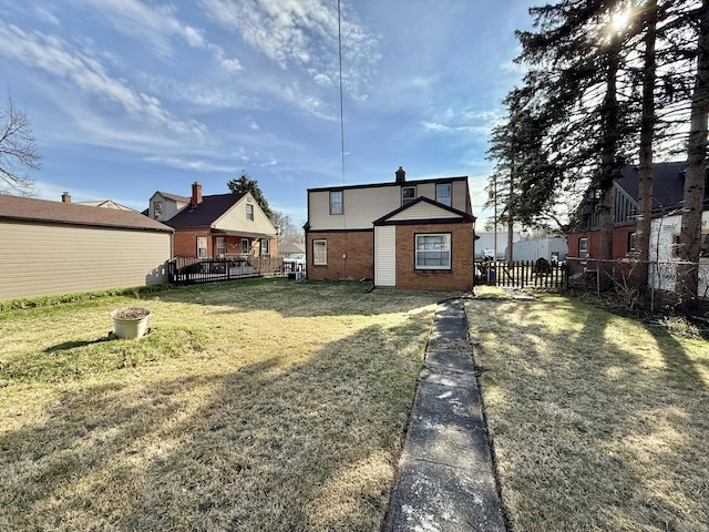 rear view of property featuring a wooden deck, fence, brick siding, and a yard