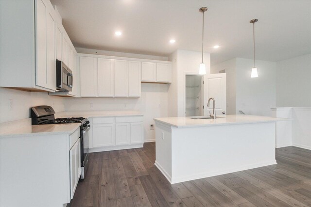 kitchen featuring white cabinets, a kitchen island with sink, stainless steel appliances, a sink, and dark wood-style floors