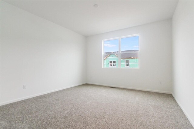 unfurnished room with baseboards, visible vents, and light colored carpet
