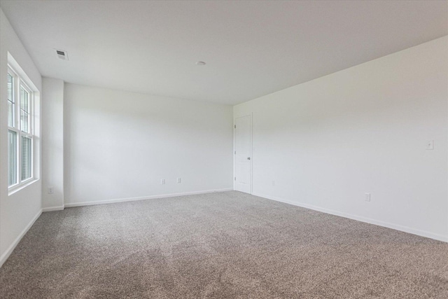 empty room with baseboards, visible vents, and carpet